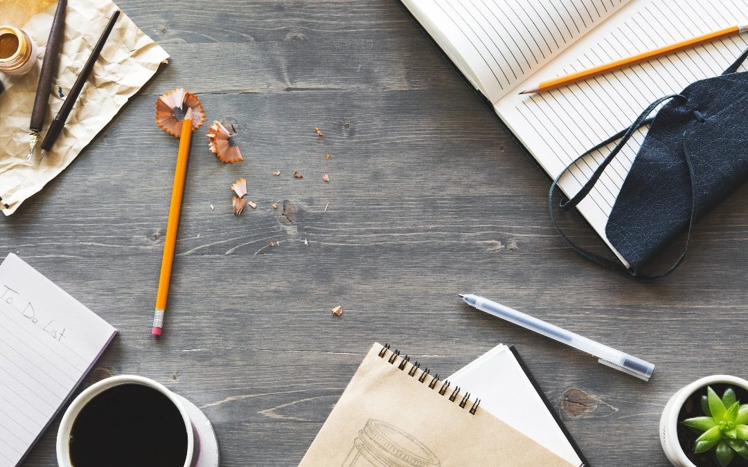 Mesa com cadernos, lápis e um café para ter mais motivação para estudar