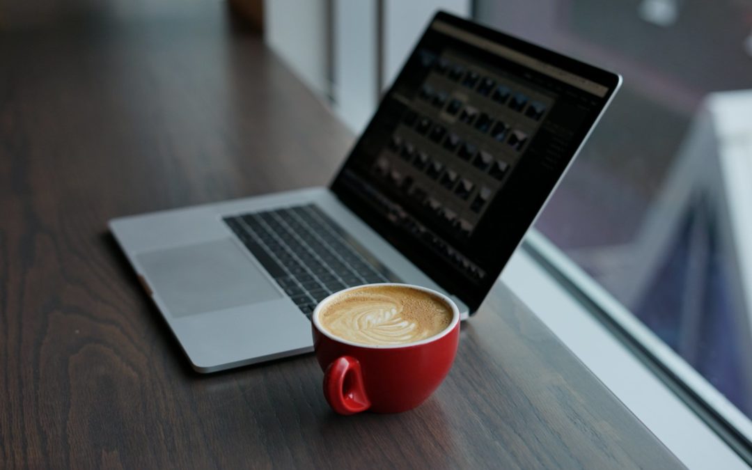 Computador com um café ao lado