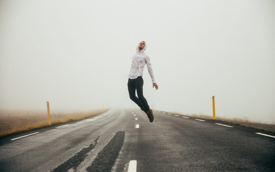 Homem saltando na estrada vazia